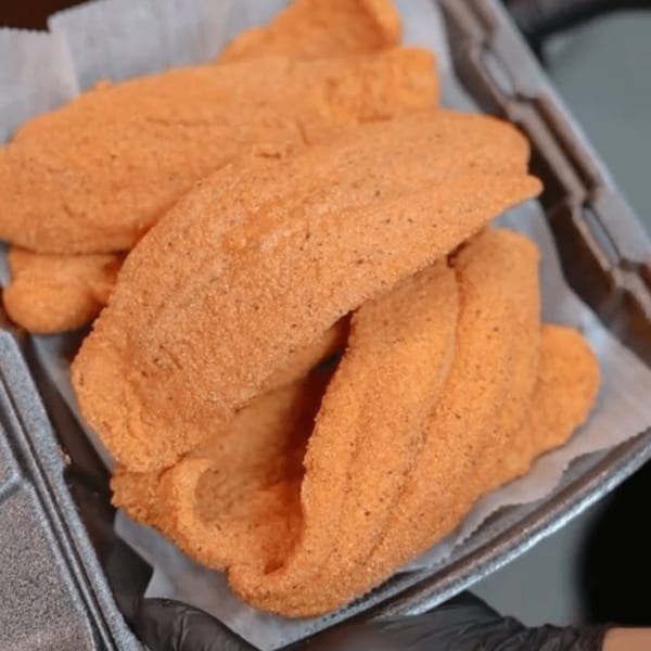 Crispy, golden-brown fried fish fillets, likely catfish, served in a takeout container from Blazin' Grill.
