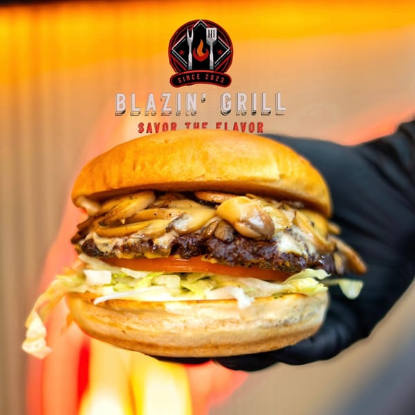 A Blazin' Grill mushroom burger with lettuce and tomato, held by a gloved hand.