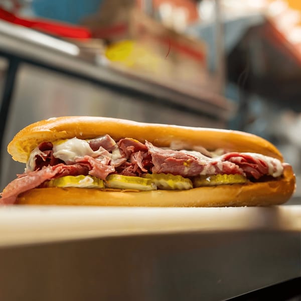 A Blazin' Grill sandwich with roast beef, pickles, and white sauce on a toasted bun.